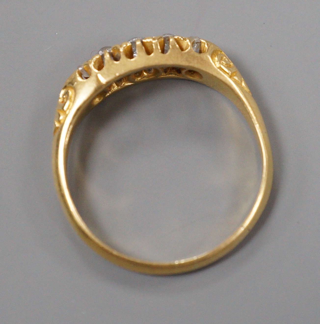 An Edwardian 18ct gold and graduated five stone diamond set half hoop ring, size M, gross weight 2.5 grams.